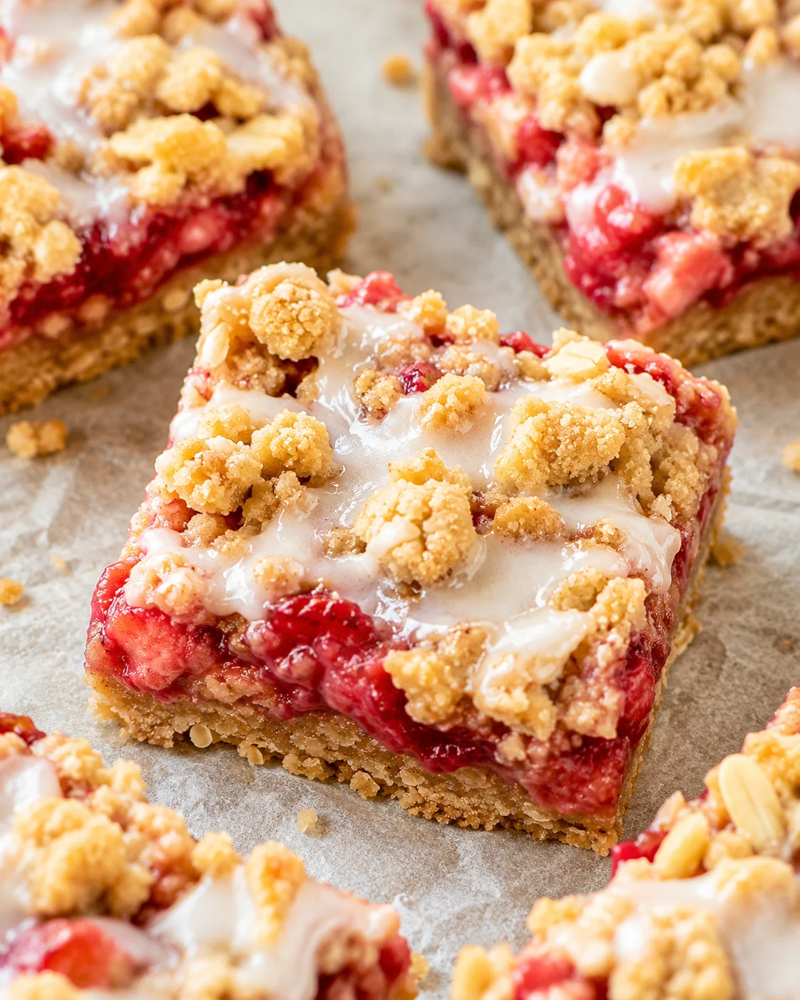 Freshly baked strawberry oatmeal bars with crumble topping on parchment paper.