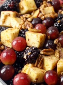 Colorful fall fruit salad with apples, grapes, blackberries, pecans, and orange dressing.