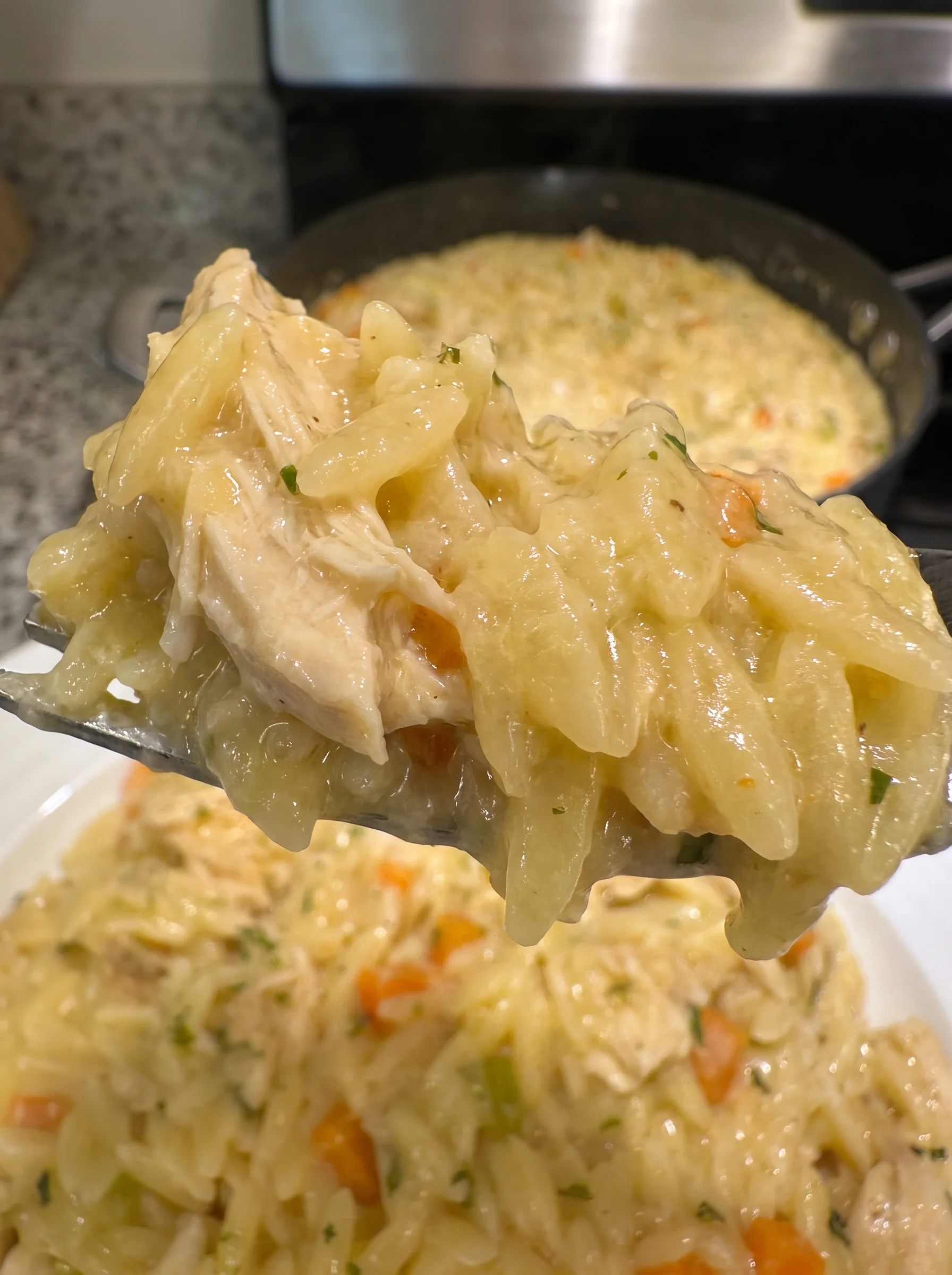 Close-up of creamy chicken pot pie orzo with vegetables and chicken in a skillet