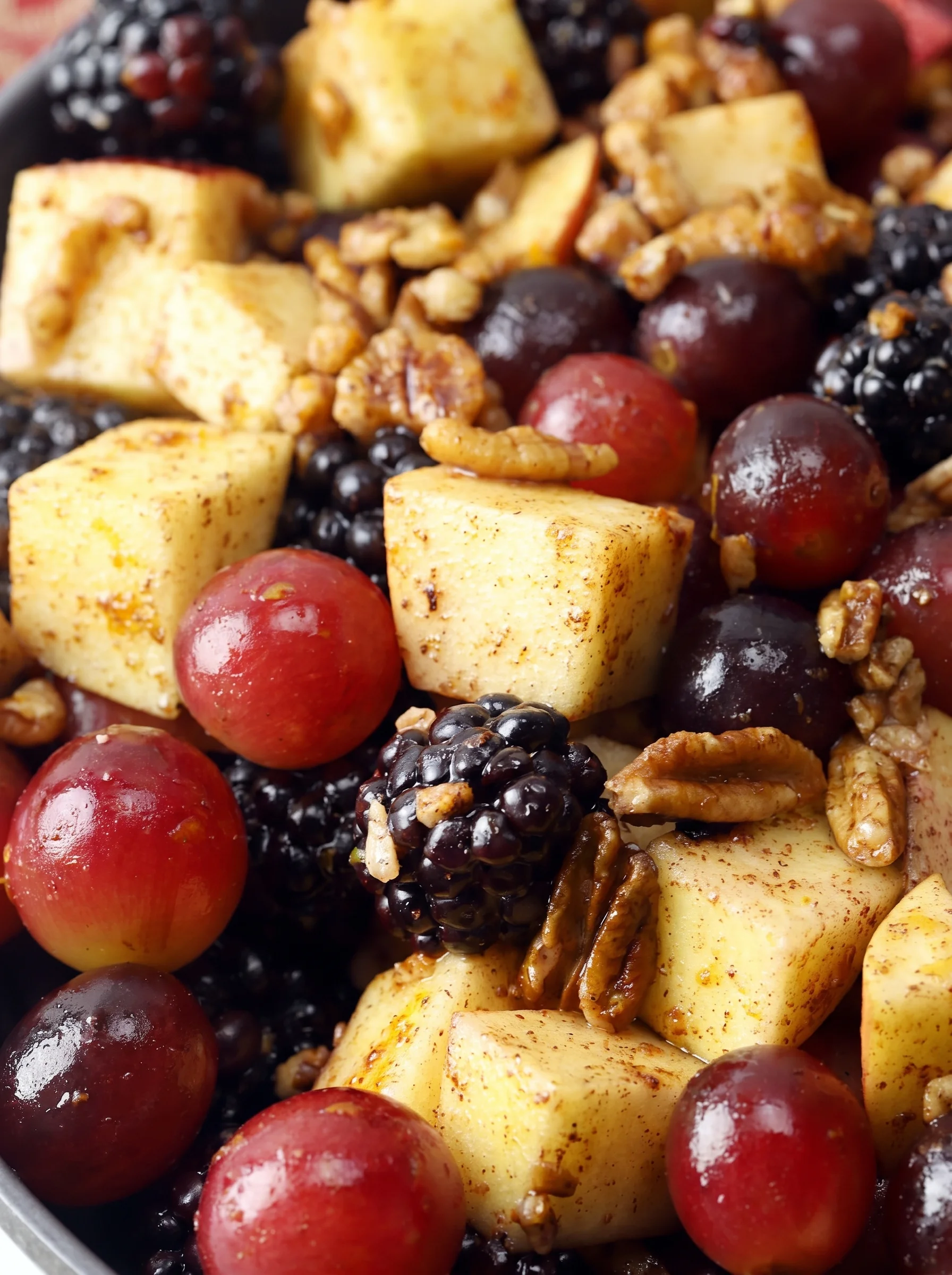 Colorful fall fruit salad with apples, grapes, blackberries, pecans, and orange dressing.