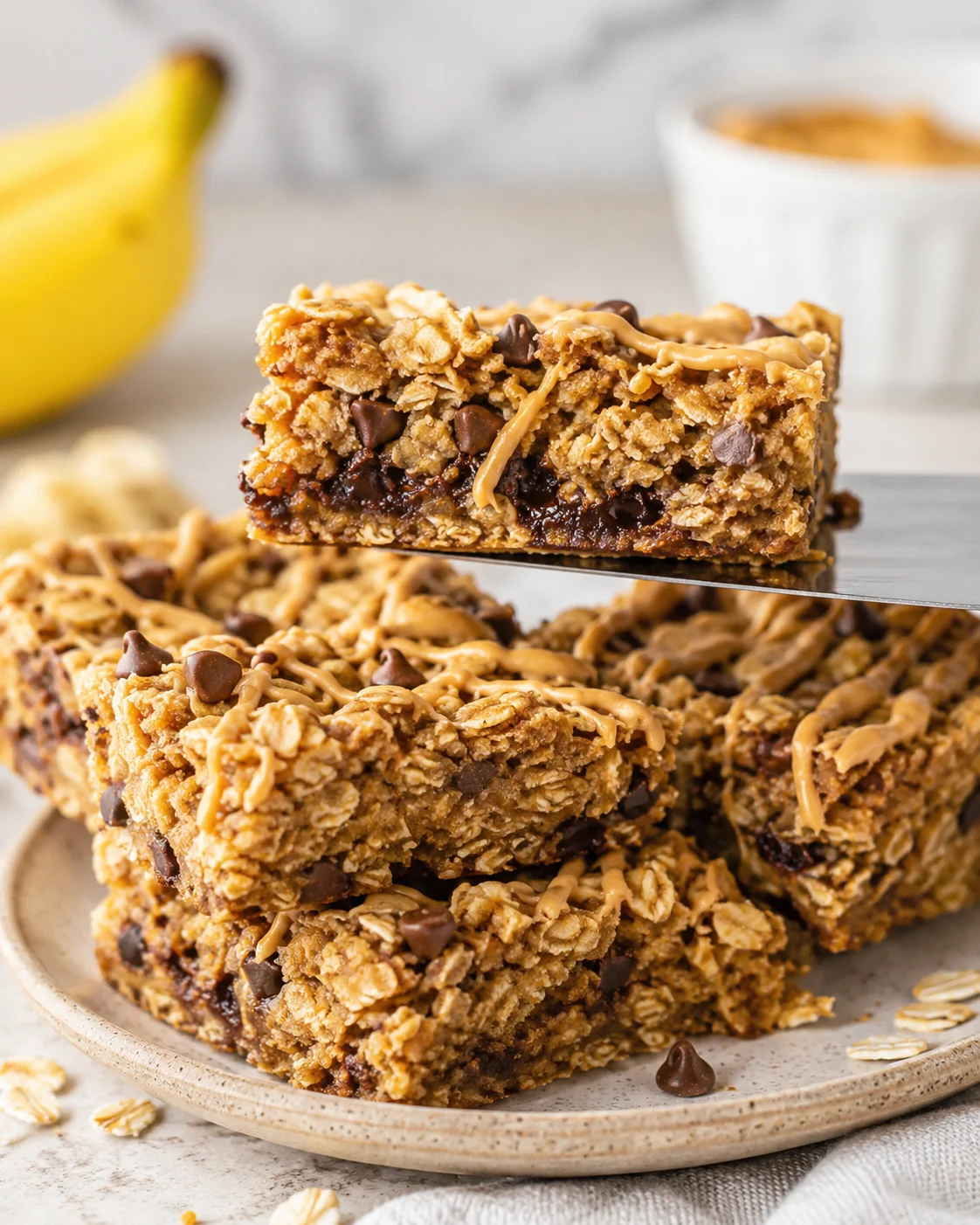 Banana Peanut Butter Oatmeal Bars Delicious homemade banana peanut butter oatmeal bars with chocolate chips on a plate.