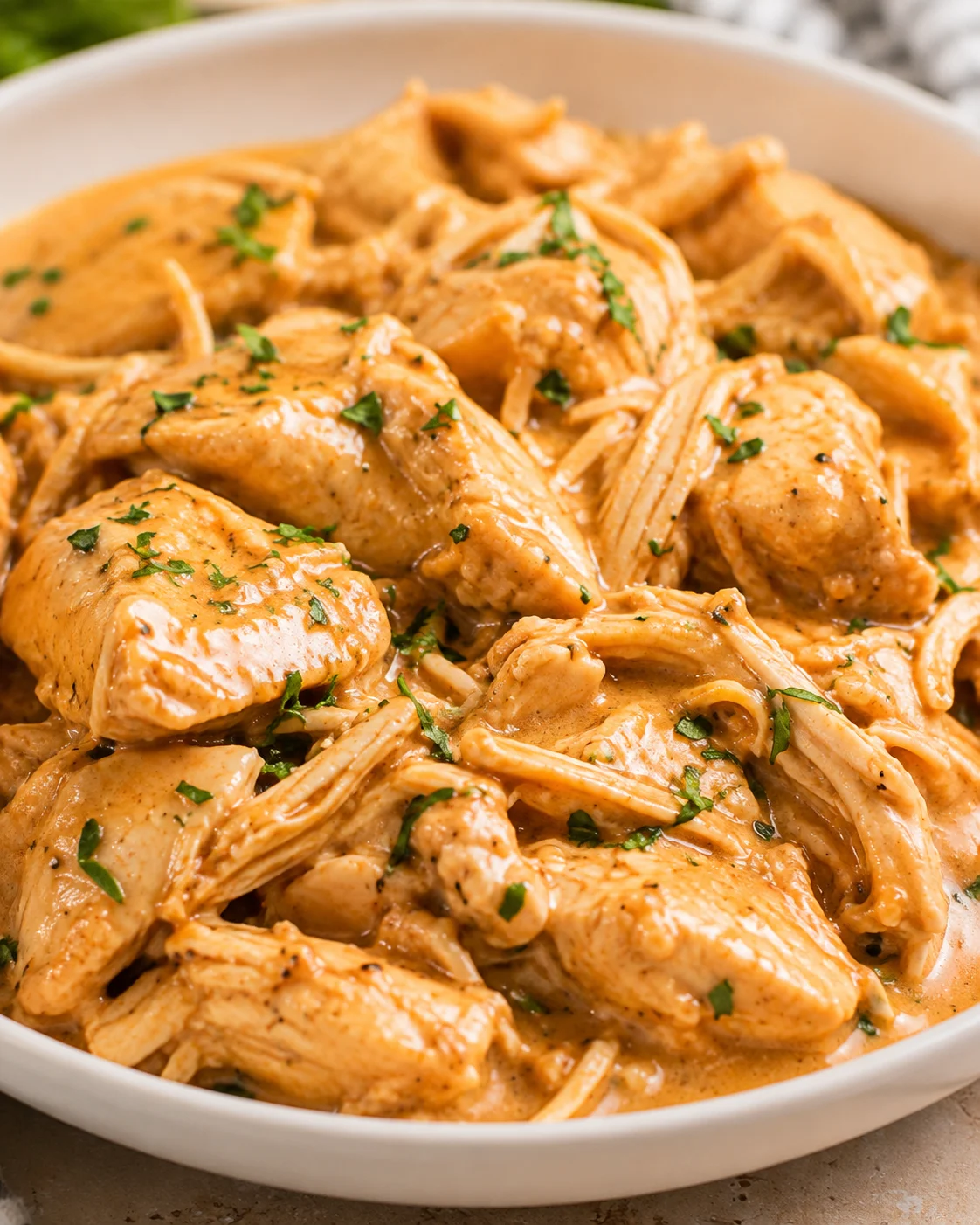 Bowl of Crock Pot Honey Mustard Chicken in creamy sauce garnished with parsley