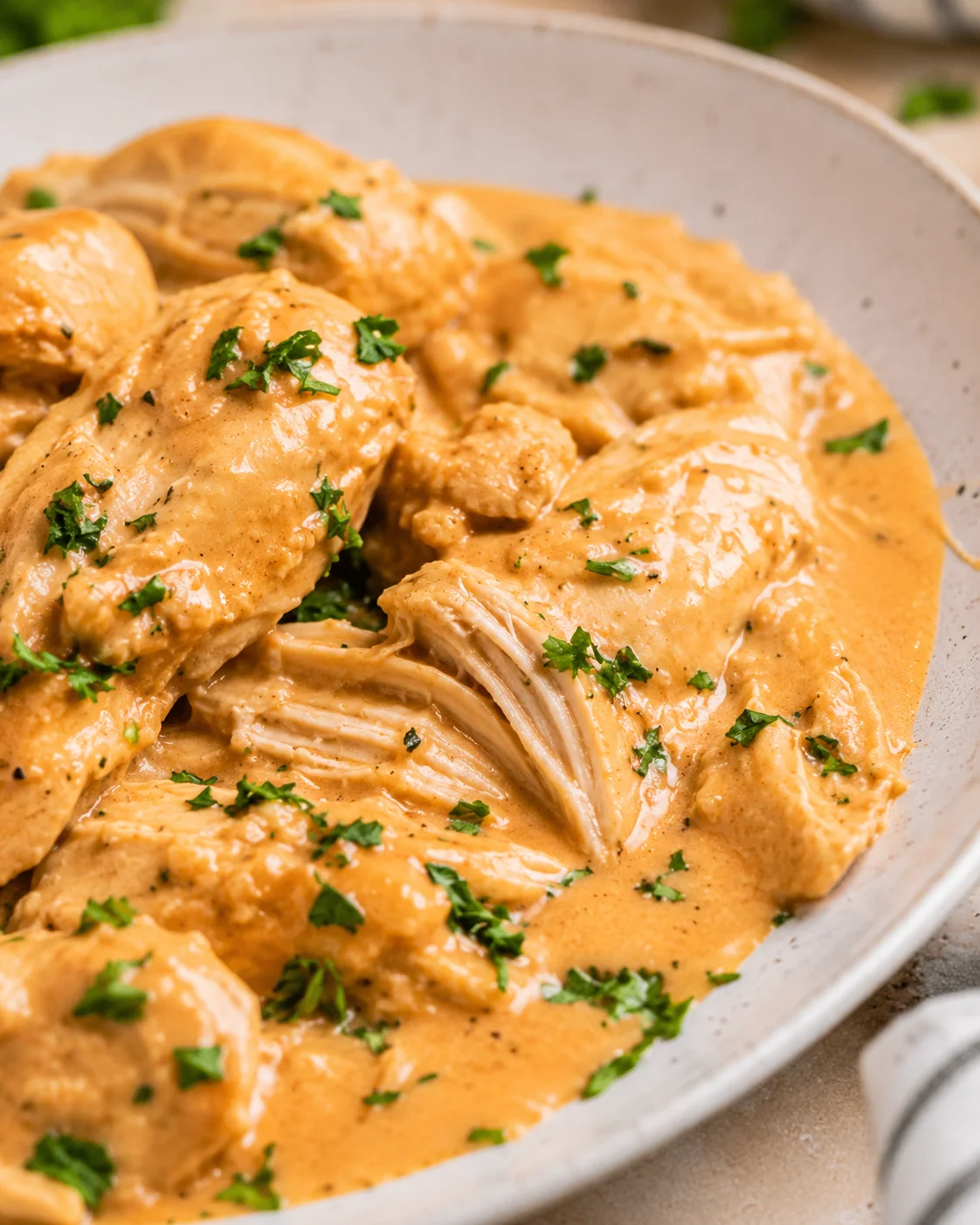Side view of Crock Pot Honey Mustard Chicken breasts and shredded pieces in creamy mustard sauce
