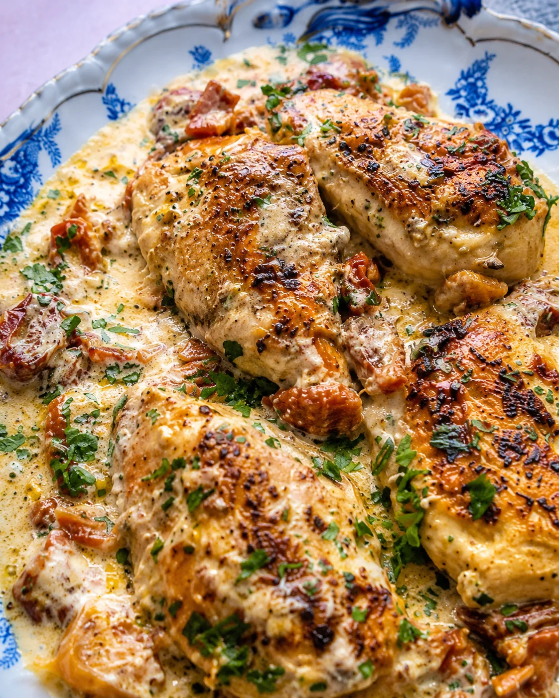 Crock Pot Marry Me Chicken in creamy sun-dried tomato sauce on a blue patterned plate