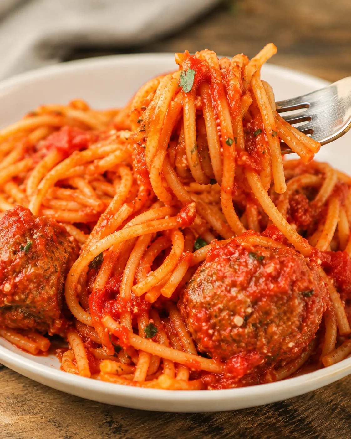Fork lifting a forkful of crock pot spaghetti with meatballs on a plate