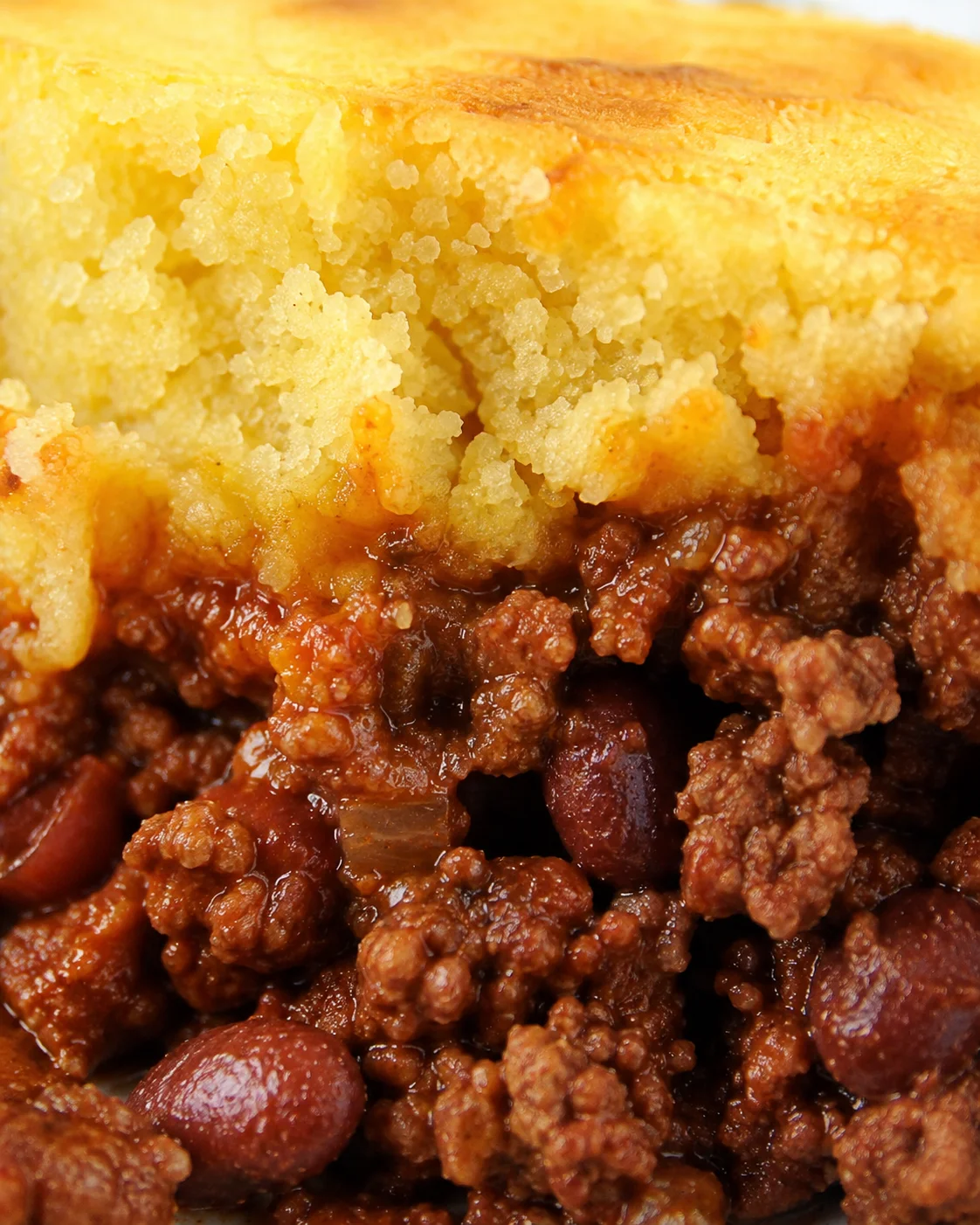 Close-up detail of Crockpot Cornbread Chili showing the crumbly cornbread and meaty chili beneath