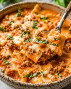 Bowl of Easy Creamy Lasagna Soup with a spoon lifting a cheesy, saucy noodle