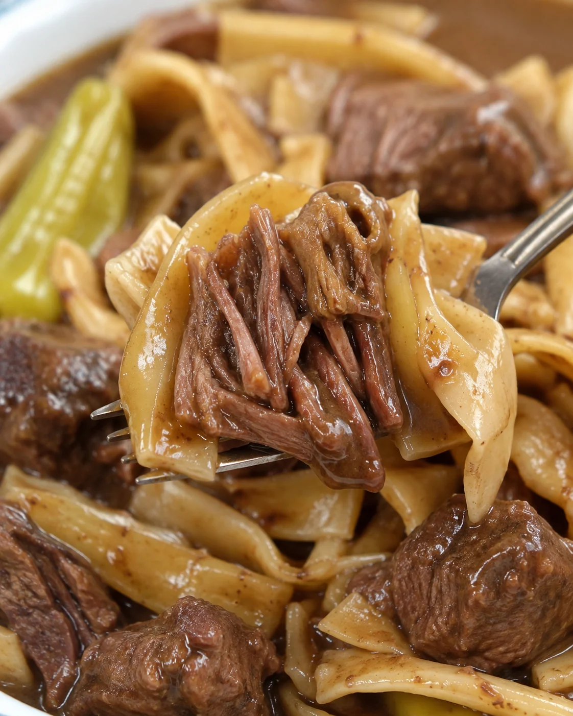 Fork lifting egg noodles and shredded beef from Crock Pot Mississippi Beef Noodles